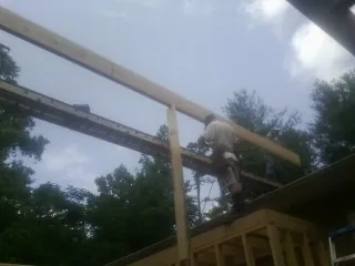 Carpenter setting a ridge beam over a new addition frame — Ice Dam Removal by Roofing Brothers in Badin