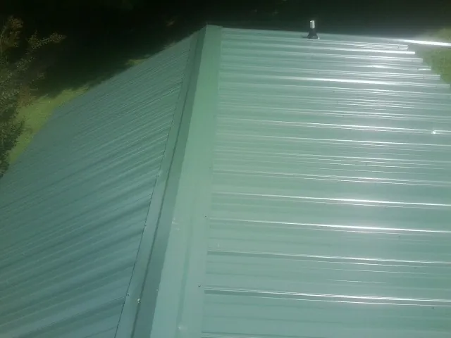 New green metal panels meeting at the ridge of a roof — Flat Roof Repair work by our crew in Badin