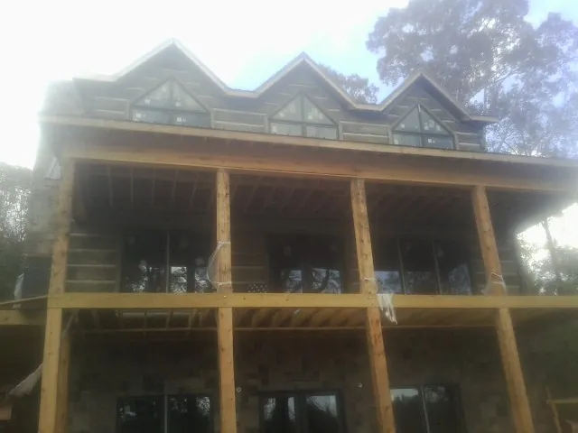 Dormers and porch framing on a large log home under construction — Roof Coating work by our crew in Badin