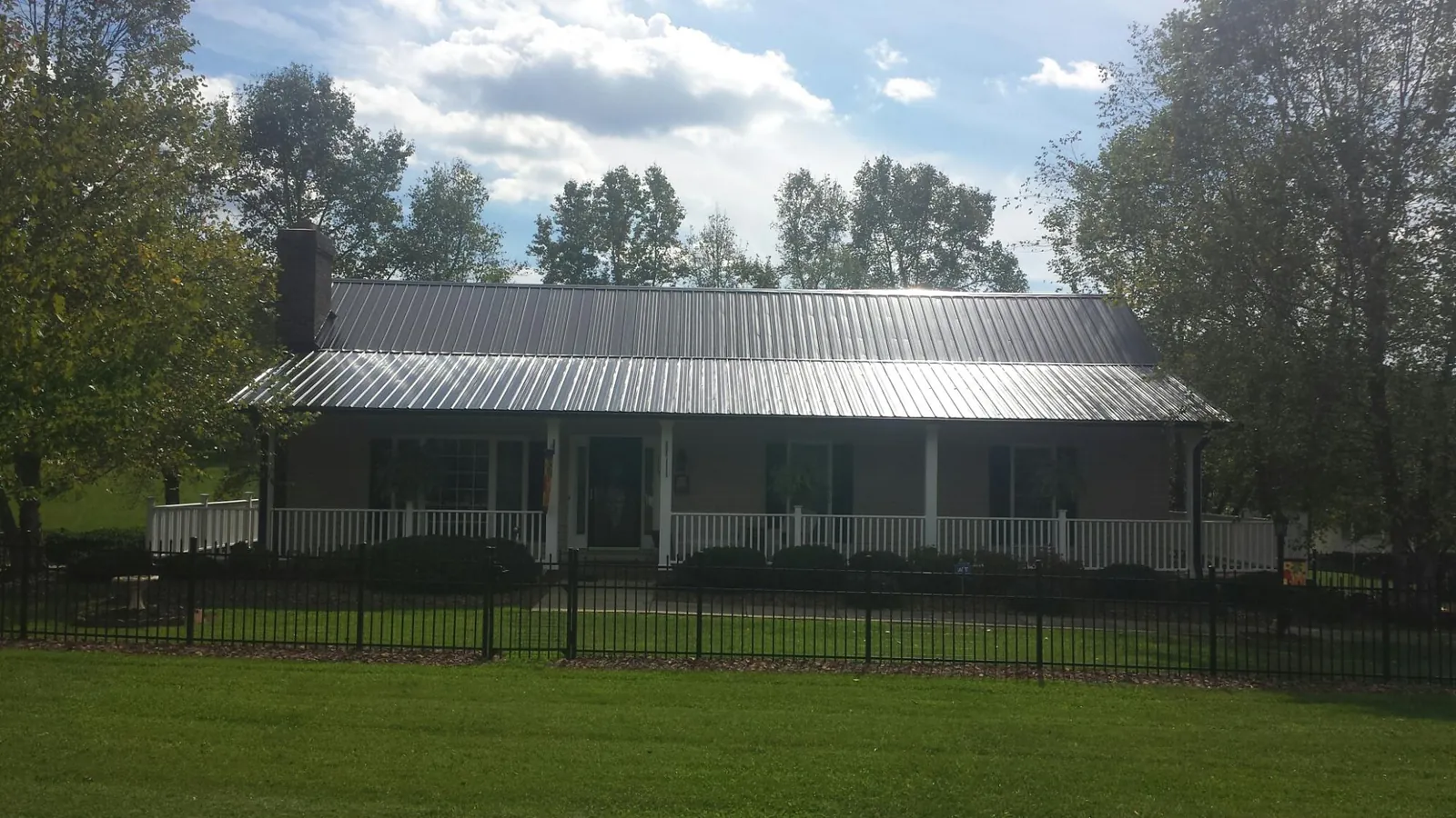 Gray metal roof on a brick ranch with a full width front porch — Gutter Guard Installation work by our crew in Badin