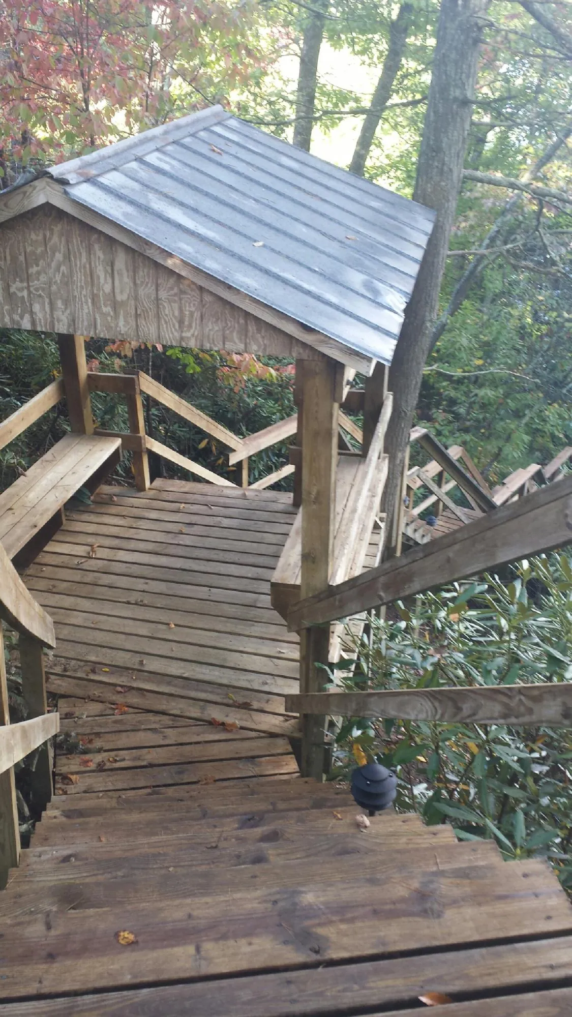 Metal roofed shelter over wooden steps on a wooded walkway — Skylight Repair & Installation work by our crew in Badin