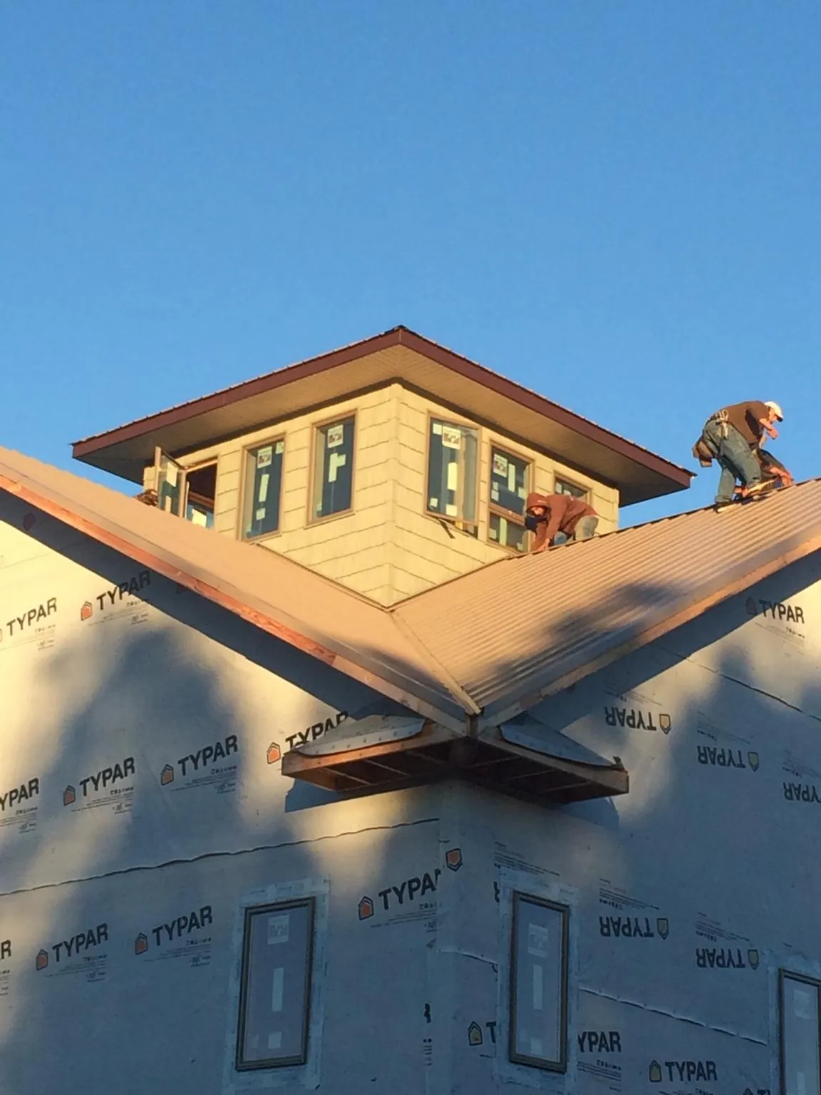 Roofers working around a rooftop cupola on a new metal roof at sunset — Roof Waterproofing in Badin by Roofing Brothers